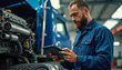 © LuisAlfonso - In a garage, a mechanic using a tablet computer diagnoses an industrial truck's diesel engine. Concept of auto repair in the auto industry