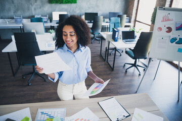 Wall Mural - Photo of positive good mood lady specialist dressed shirt reading documents indoors workstation workshop