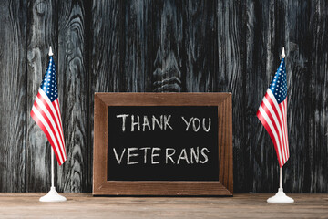 Sticker - A rustic display featuring small American flags and a chalkboard expressing gratitude to veterans on Memorial Day.