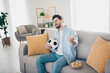 © deagreez - Photo of handsome alone mature age adult man staying home in living room holding ball dissatisfied watching his team losing game