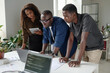 © AnnaStills - African American coworkers looking at codes together, they focused on working process
