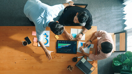 Executive manager explain financial graph to colleague at meeting room. Top aerial view of diverse marketing team sharing idea and planning strategy while sitting at table with tablet. Convocation.