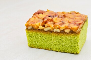 cake with chocolate A square cake with a bright green base made from water meal The top layer is covered with caramel mixed with large nuts giving it a crunchy texture. It goes well with tea or coffee