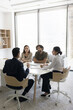 © fizkes - Diverse business specialists stakeholders team hold briefing meeting conversation discuss idea negotiate. Professional managers gather by conference desk for teamwork on project startup. Vertical shot