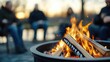 © Pinklife - A group of friends sits in a circle around a glowing evening fire pit, sharing stories and laughter amid a scenic winter background, capturing an intimate warm moment.