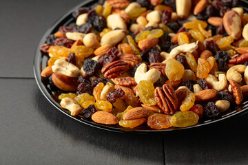 Mix of dried nuts and raisins on a black background.