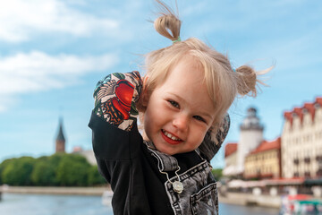 a little child toddler girl in a denim jumpsuit travels to the fishing village in kaliningrad, an ac