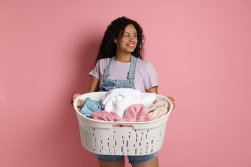 Canvas Print - Happy woman with basket full of laundry on pink background