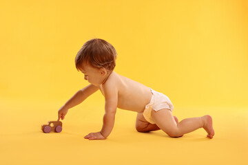 Canvas Print - Little child in diaper with toy on orange background