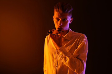 Poster - Young man recording voice message via smartphone on color background with neon lights, space for text