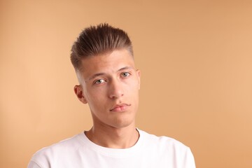 Wall Mural - Confident young man with stylish haircut on light brown background. Space for text