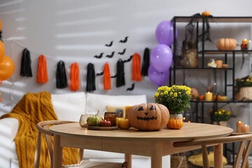 Poster - Halloween celebration. Pumpkin with creepy face, candles and flowers on wooden table in decorated room