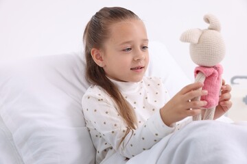 Wall Mural - Cute little girl with toy bunny on bed in hospital