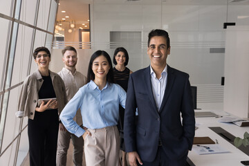 Poster - Happy successful Indian company leader man standing in front of team in office meeting room workspace, looking at camera for portrait, promoting corporate teamwork, unity, successful collaboration