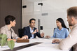 © fizkes - Indian business professional man talking to coworkers at meeting, offering ideas for brainstorming, speaking to colleagues at large office table. Multiethnic group of managers teamwork