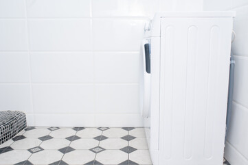 Washing machine in a room with white tiles. Space for text