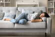 © fizkes - Sleepy pretty young woman resting on grey sofa at cozy home, enjoying calm leisure, relaxation, sleeping at daytime, lying on side, suffering from insomnia, sleeping disorder at night