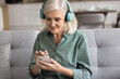 © fizkes - Focused attractive woman wear modern wireless headphones listen music, choose song using mobile application of online digital streaming services, chatting with family, watch videos, enjoy device usage