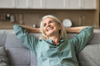 © fizkes - Cheerful aged woman resting on cozy couch with smile on her face, looking away feel happy, spending untroubled time at home, enjoy comfort and smart home climate control and silent domestic appliances