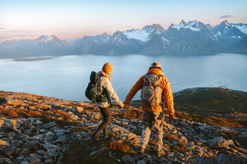 Wall Mural - couple with backpacks hiking in norway mountains man and woman holding hands traveling active vacati