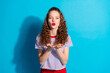 © deagreez - Young woman in striped shirt blows a kiss against a vibrant blue background