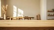 © Elshad Karimov - A vacant, wooden table rests in a Scandinavian-inspired living room, its surface smooth and unadorned. The background is a gentle blur, hinting at a space filled with muted tones