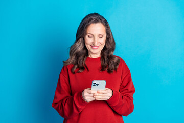 Wall Mural - Portrait of nice aged woman use phone wear red sweater isolated on blue color background