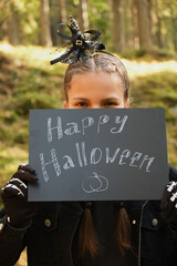 teenage girl holding chalk sign happy halloween outside