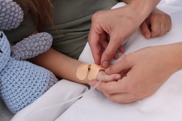 Wall Mural - Doctor examining little girl on bed at hospital, closeup