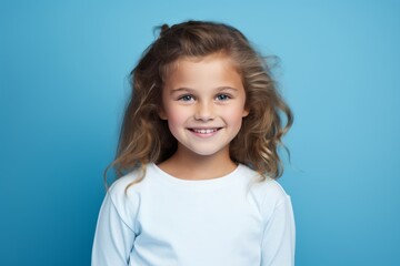 Portrait of a cute little girl with long curly hair on a blue background