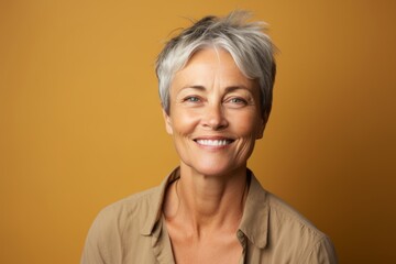 Portrait of happy senior woman with short grey hair on yellow background