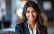 © James - Portrait of a smiling, beautiful young Indian business woman in a suit with an blurred office background.