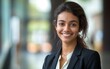 © James - Portrait of a smiling, beautiful young Indian business woman in a suit with an blurred office background.