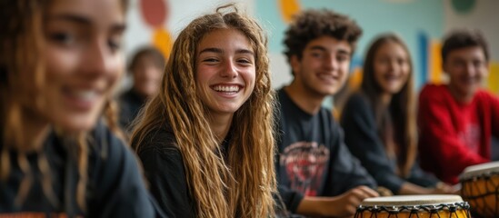 A group of young people playing drums together, smiling and looking at the camera.