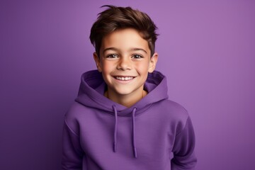 Smiling little boy in purple hoodie posing over violet background.