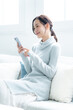 © ponta1414 - リビングのソファで携帯を持つ笑顔の女性