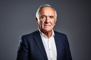 Portrait of a senior businessman over grey background. Looking at camera.