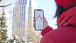 © nurman - Woman in a red coat checks the stock market on her phone.