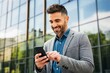 © Henhen - Man in a suit using a smartphone outside a glass building.