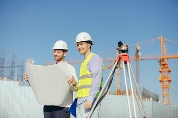 team of building experts working with drawings with surveyor level at new construction site