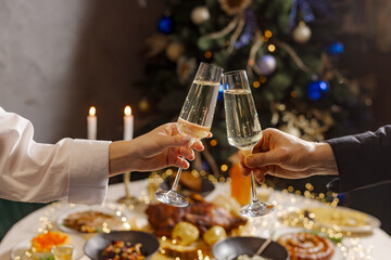 hands with glasses of champagne close-up on the background of a festive Christmas table