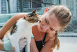 © Evgenii Bakhchev - A young woman bonding with a friendly cat at an animal shelter during a sunny afternoon visit to help rescue pets in need of a loving home