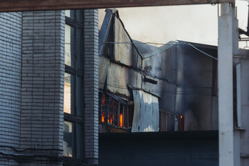 Wall Mural - Massive large blaze fire in the city, blazing warehouse factory, storage building is burning, firefighters team putting out the fire, firemen on duty, extinguish the fire, arson, burning house damage