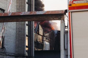 Wall Mural - Massive large blaze fire in the city, blazing warehouse factory, storage building is burning, firefighters team putting out the fire, firemen on duty, extinguish the fire, arson, burning house damage