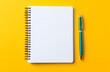 © Mahmud - A blank white spiral notebook with a pen on a yellow background design