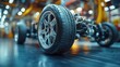 © ROY - Close-up of a car chassis with a tire and wheel on a factory floor.