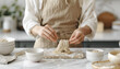 © Oleksiy - Woman making soba (buckwheat noodles) with knife at white marble table indoors, closeup
