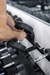 © andov - A man in a gym picks up a dumbbell to do weightlifting.