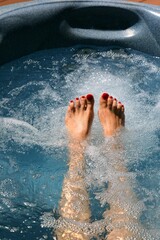 feet of young woman with red painted toenails are relaxing in a hot tub