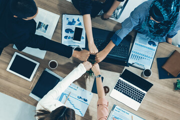 Businessmen and businesswomen joining hands in group meeting at multicultural office room showing teamwork, support and unity in business. Diversity workplace and corporate people working concept. uds